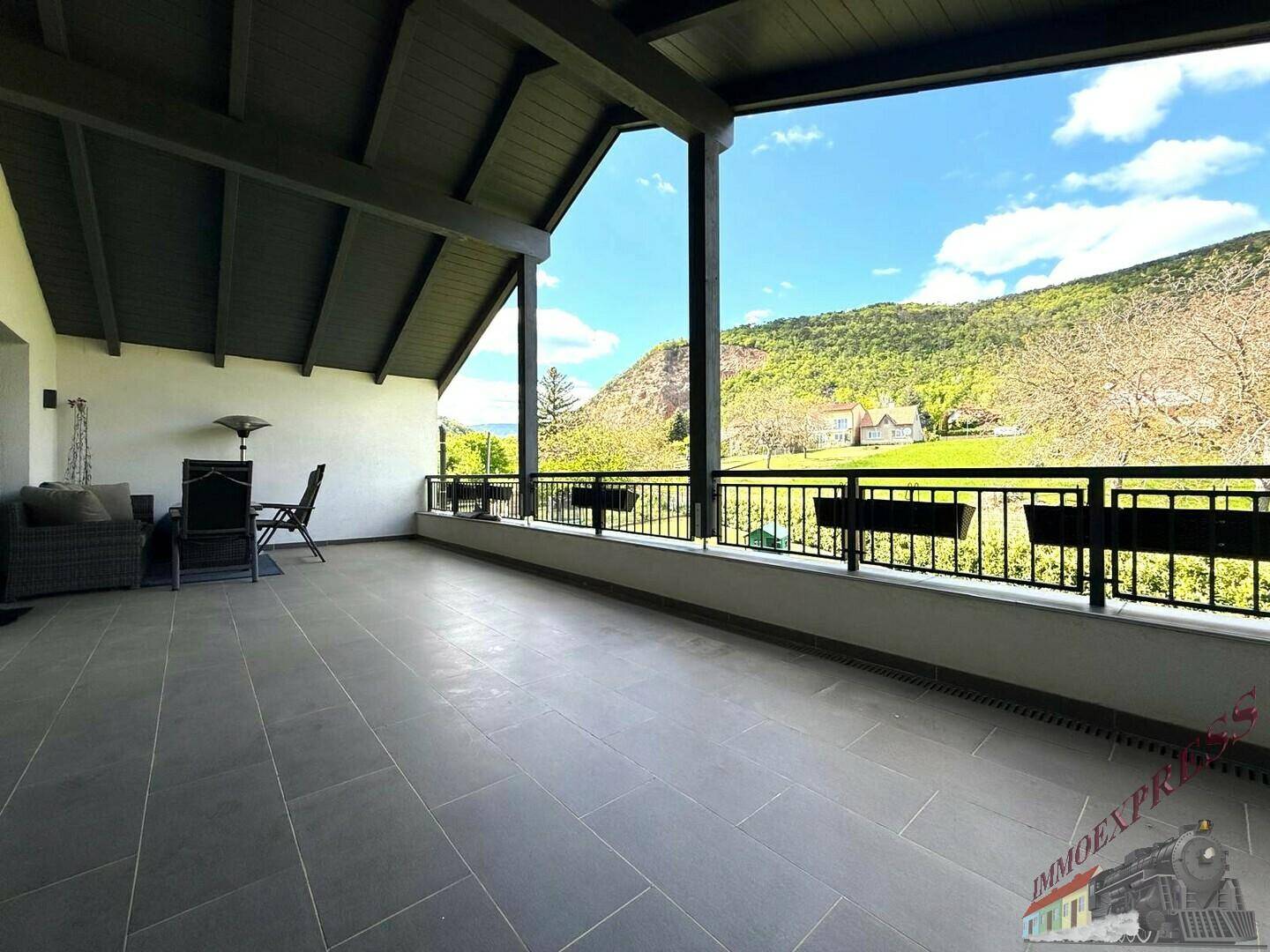 Geräumiger Balkon mit Panoramablick auf die umliegende Berglandschaft und viel Sonnenlicht.