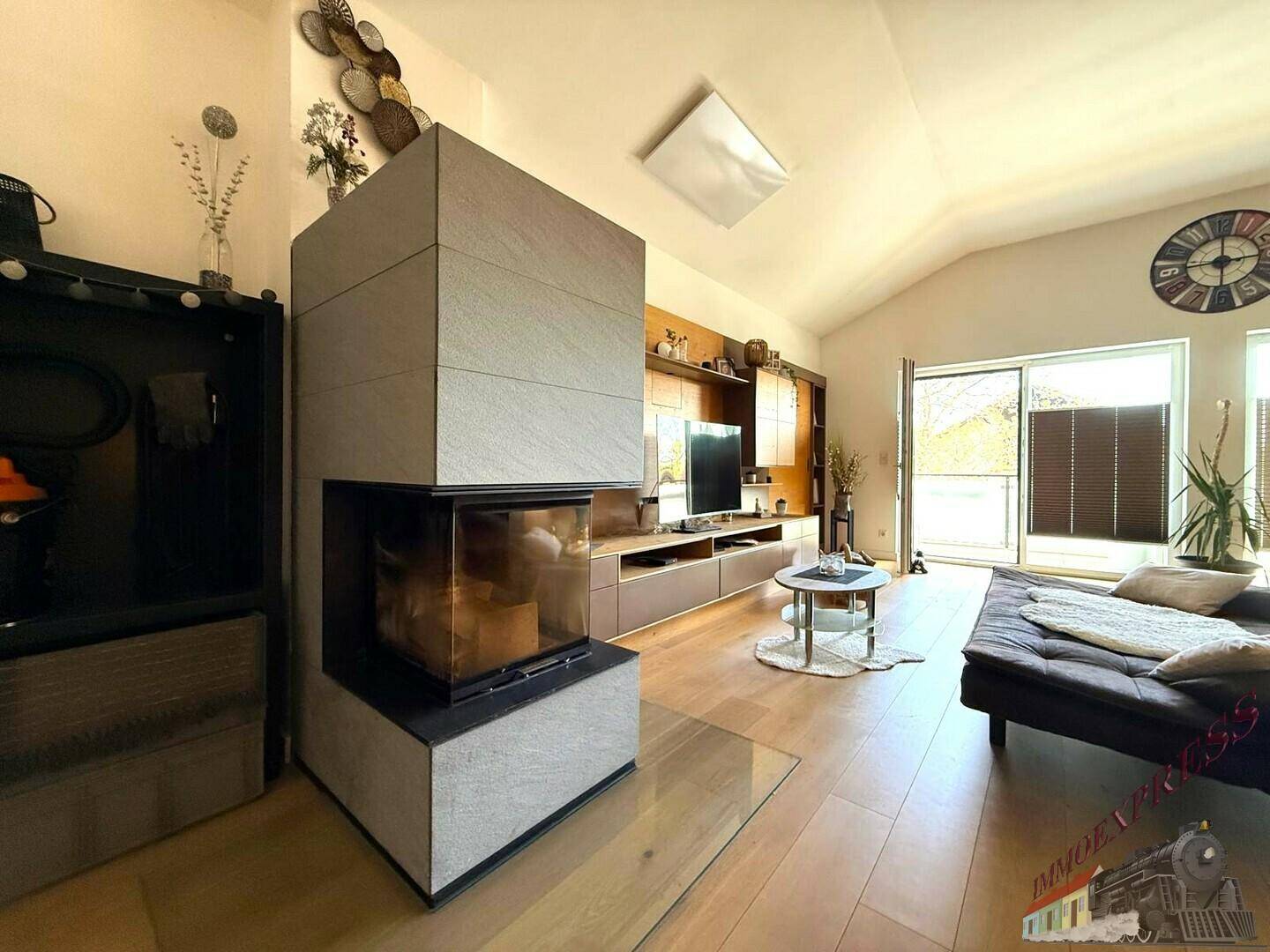 Gemütliches Wohnzimmer mit modernem Kamin, Holzboden und Zugang zu einem Balkon.