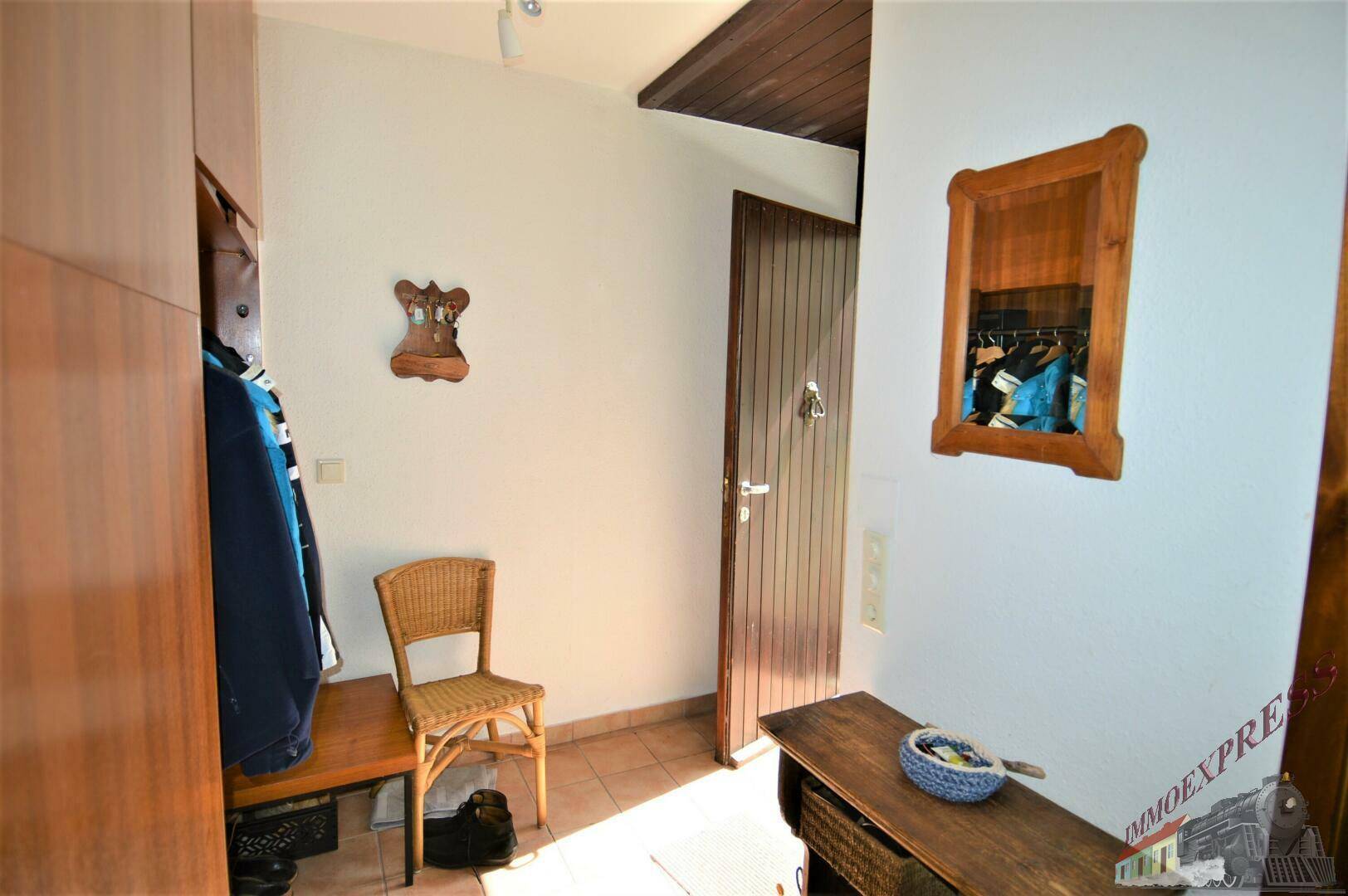 Eingangsbereich mit Garderobe, Sitzgelegenheit und Terrakotta-Fliesenboden.