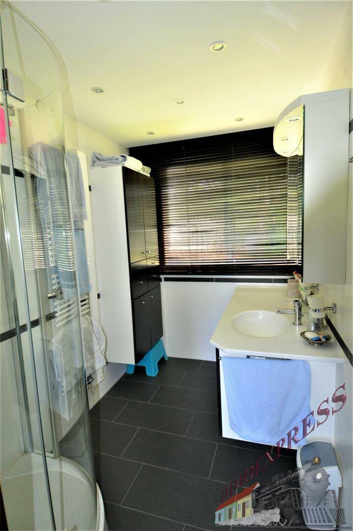 Modernes Badezimmer mit dunklen Fliesen, Waschtisch und Duschkabine.