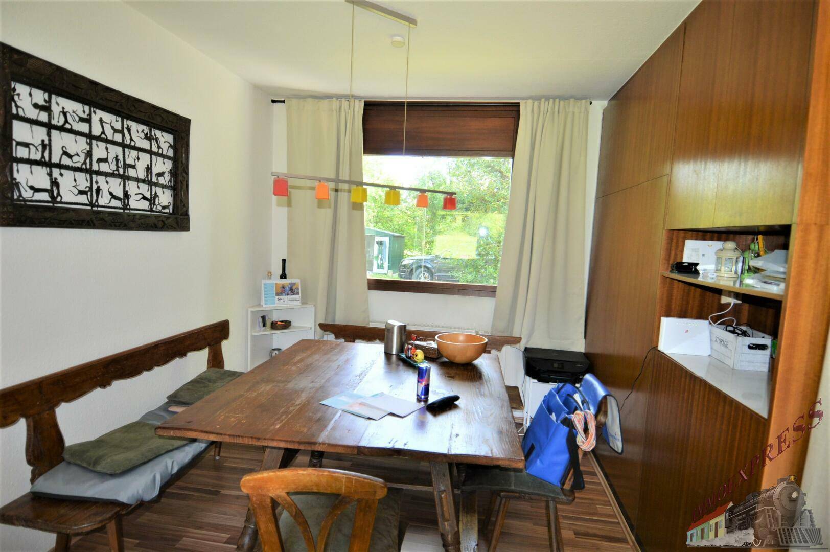 Rustikaler Essbereich mit Holztisch und Bank, umgeben von Holzvertäfelung und Fensterblick.