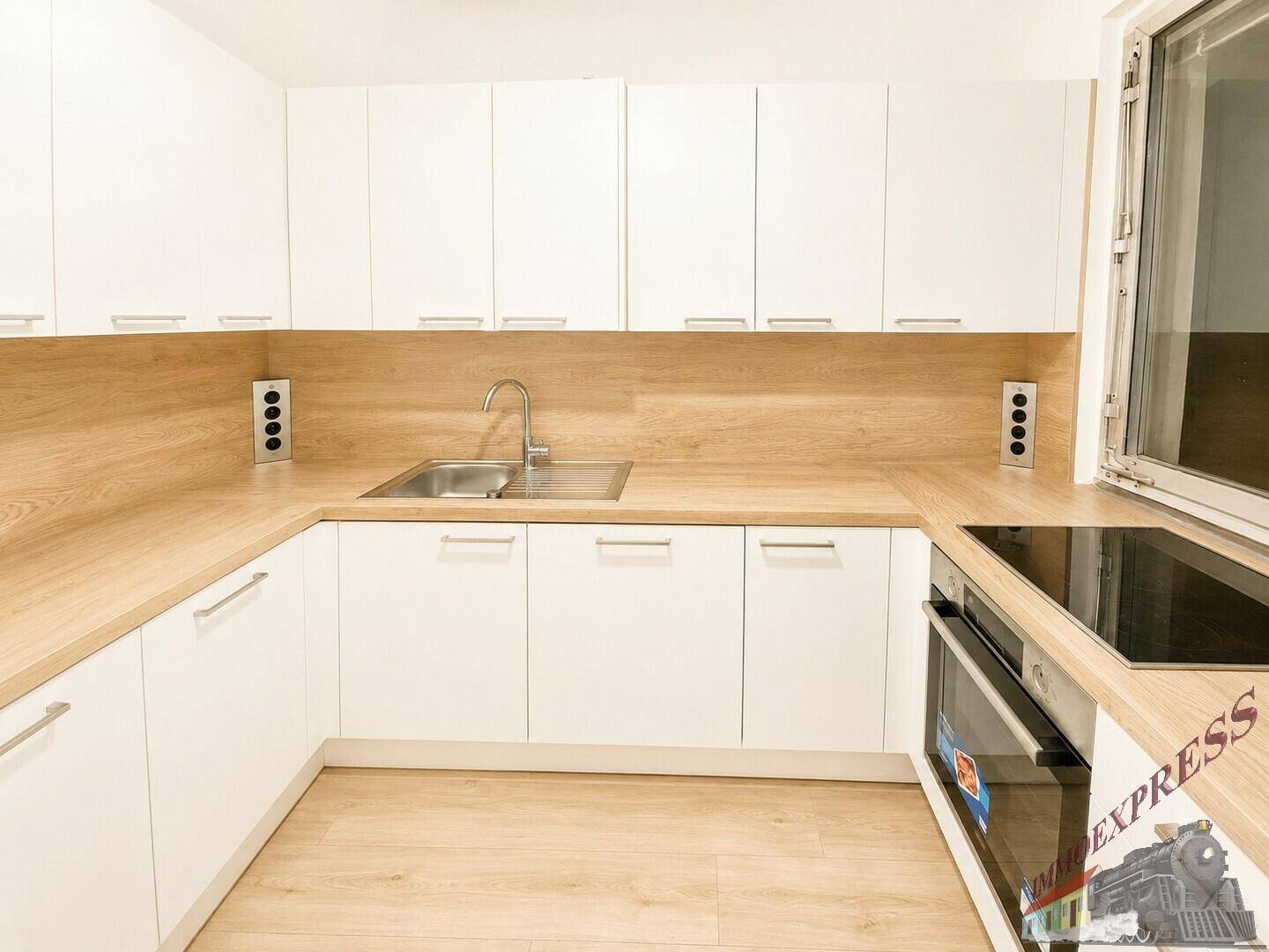 Moderne Einbauküche mit weißen Schränken, Holzoptik-Arbeitsplatten und Induktionskochfeld.