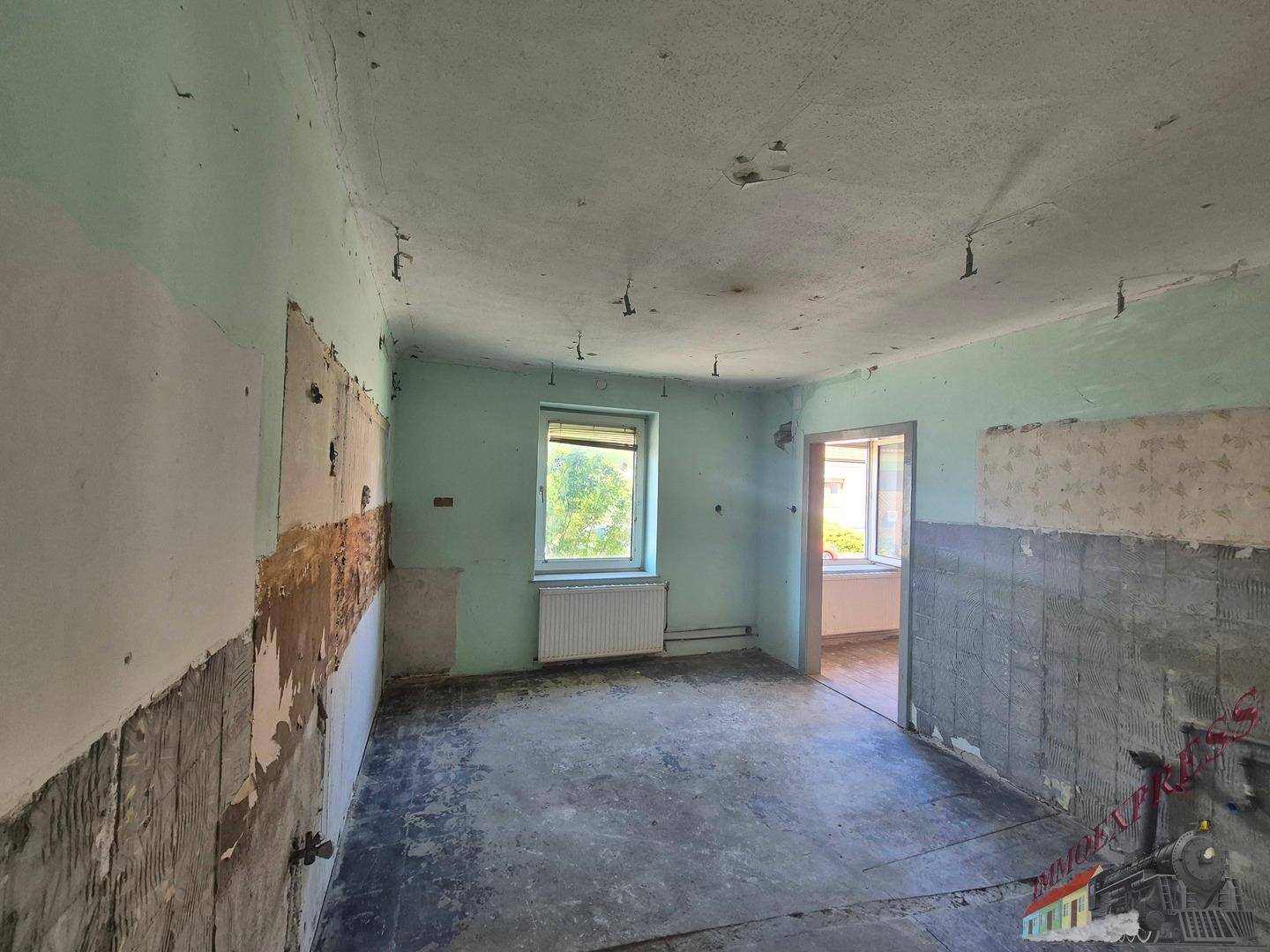 Renovierungsbedürftiger Raum, möglicherweise eine Küche, mit Fenster und Türrahmen.