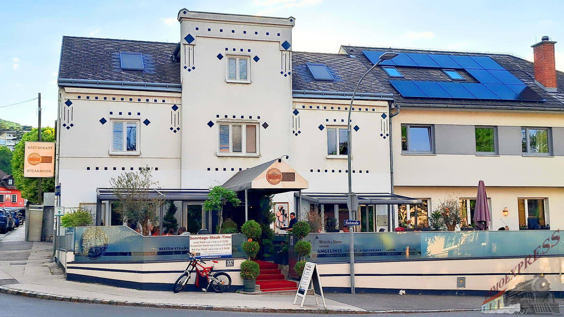 Historisches Gebäude mit moderner Fassade, Restaurant im Erdgeschoss und Solarpaneelen auf dem Dach.