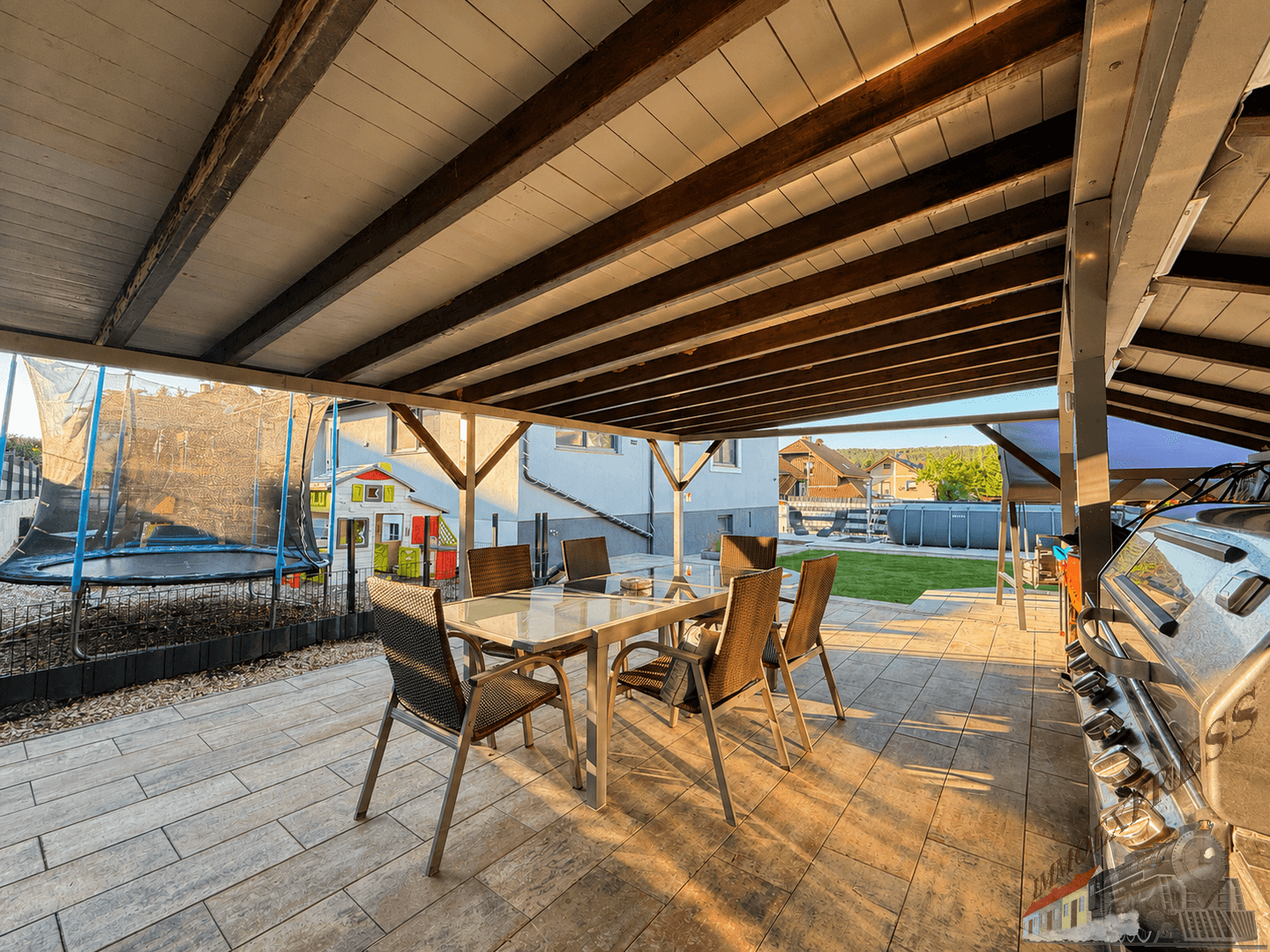Überdachte Terrasse mit Esstisch, Gartenmöbeln und Blick auf den Garten.