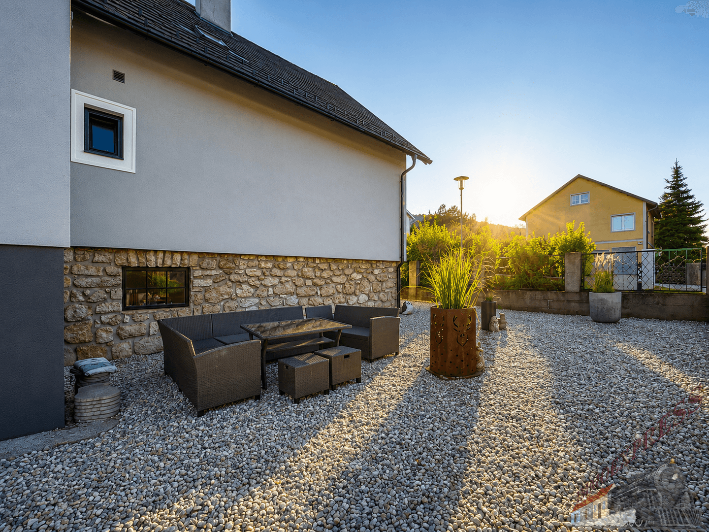 Kiesgarten mit Sitzbereich, Pflanzen und Blick auf die umliegende Landschaft.