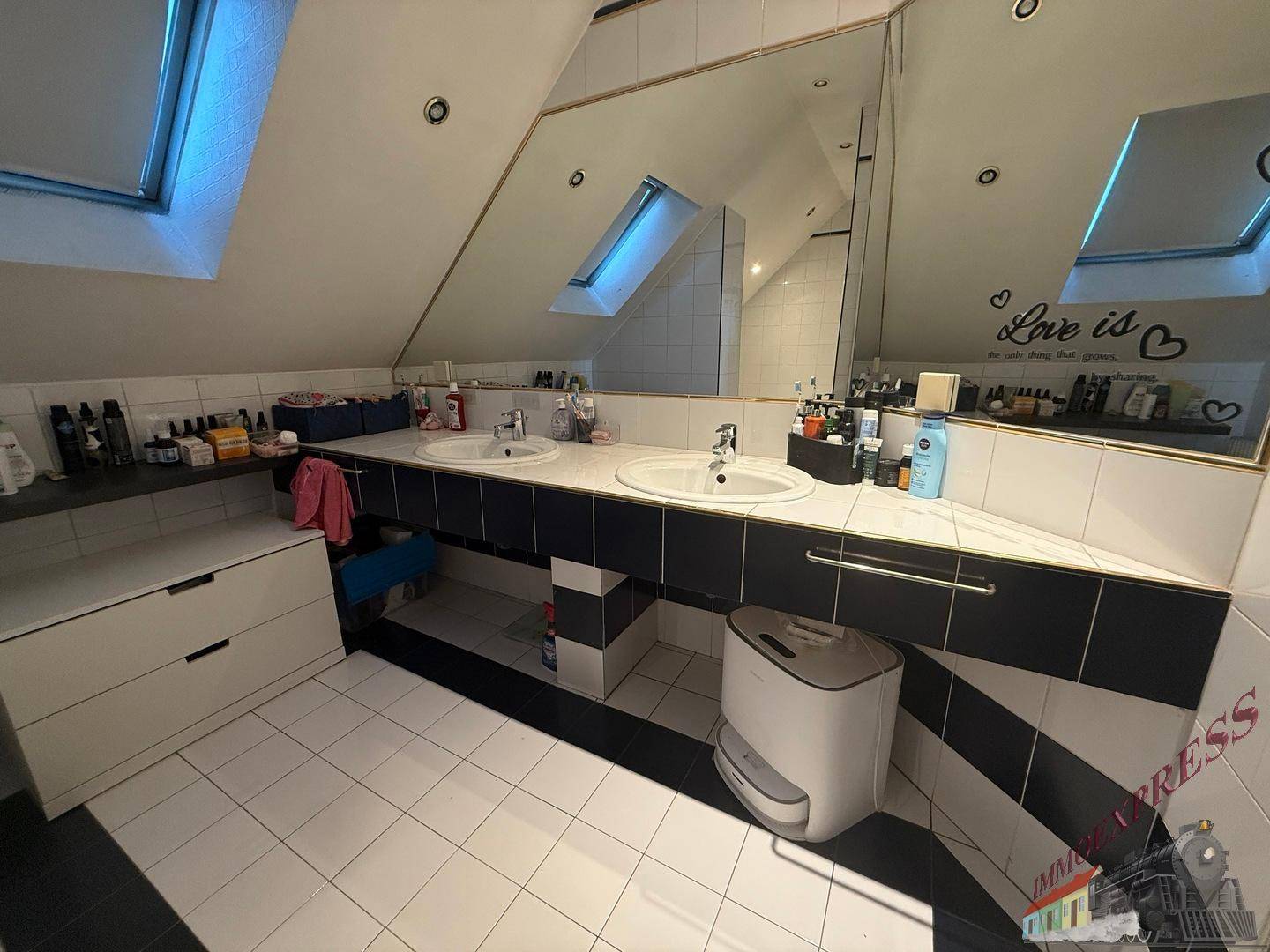 Helles Badezimmer im Dachgeschoss mit Doppelwaschbecken, großem Spiegel und Dachfenstern.
