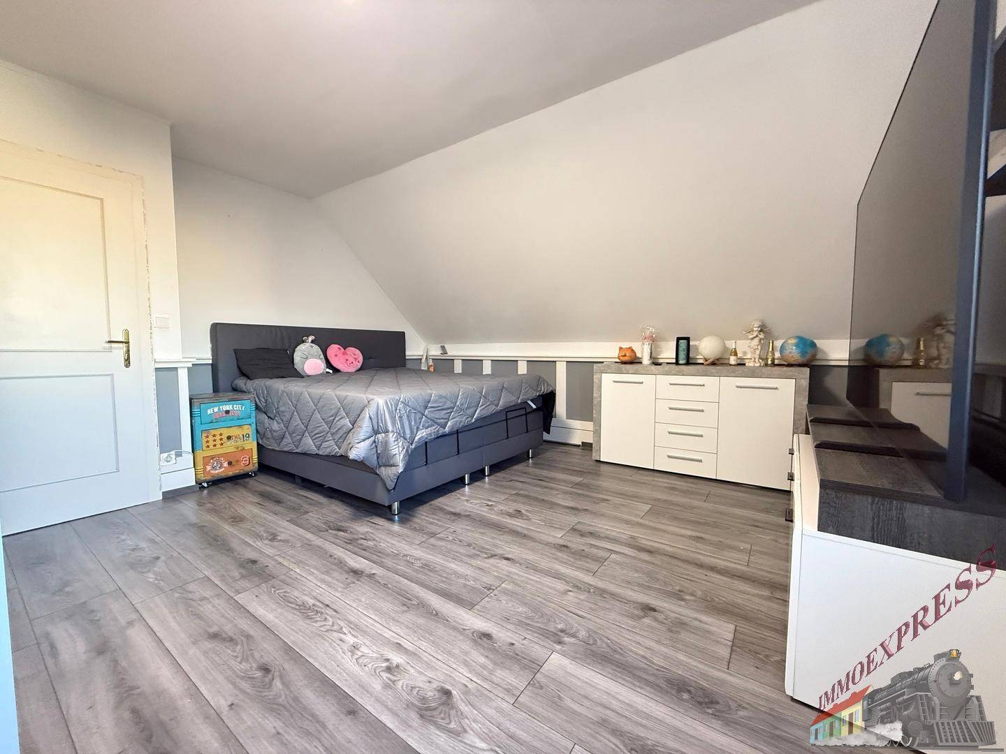 Helles Schlafzimmer im Dachgeschoss mit Laminatboden und modernem Bett.