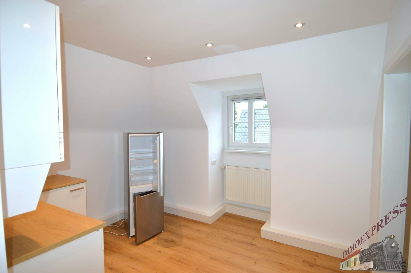 Helle Küche in Dachgeschosswohnung mit schrägen Wänden und Fenster.