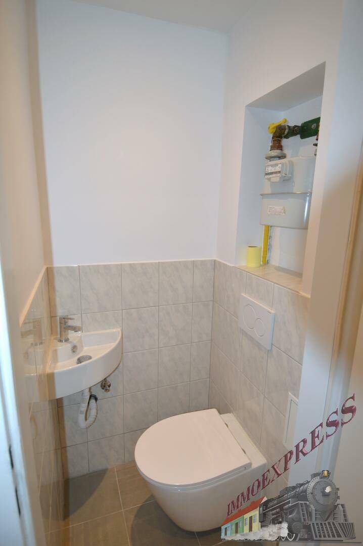 Kleines Gäste-WC mit wandhängendem WC und Waschbecken.