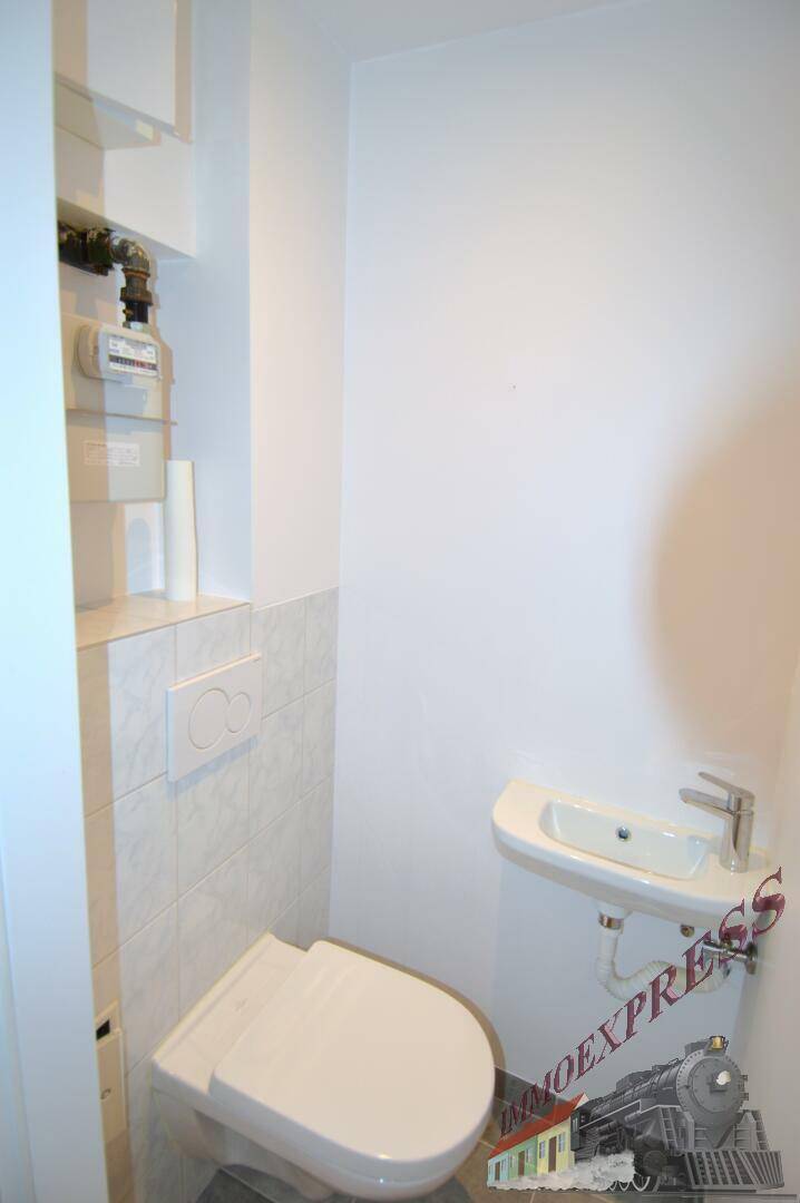 Kleines Gäste-WC mit Wand-WC, Waschbecken und hellen Fliesen.
