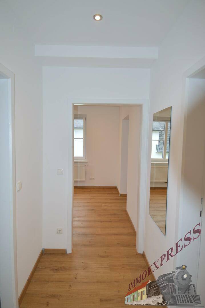Langer, heller Flur mit Laminatboden und Zugang zu weiteren Räumen.