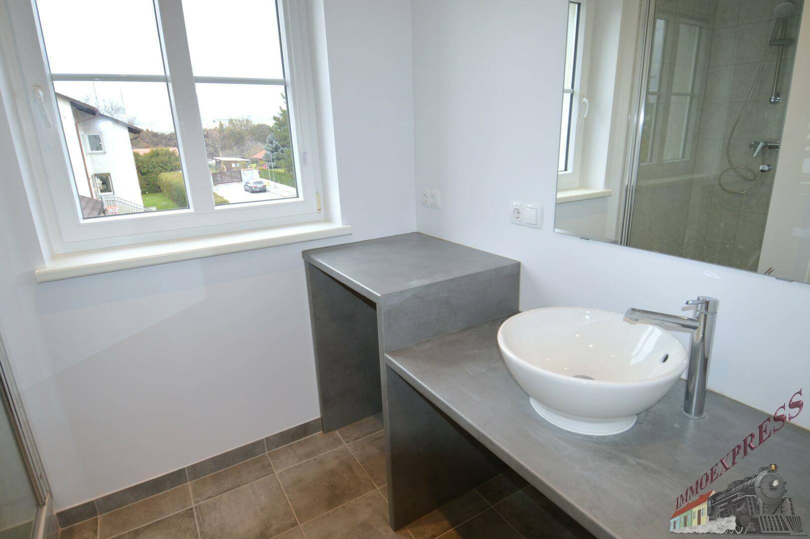 Modernes Badezimmer mit Aufsatzwaschbecken, großem Spiegel und Fenster.