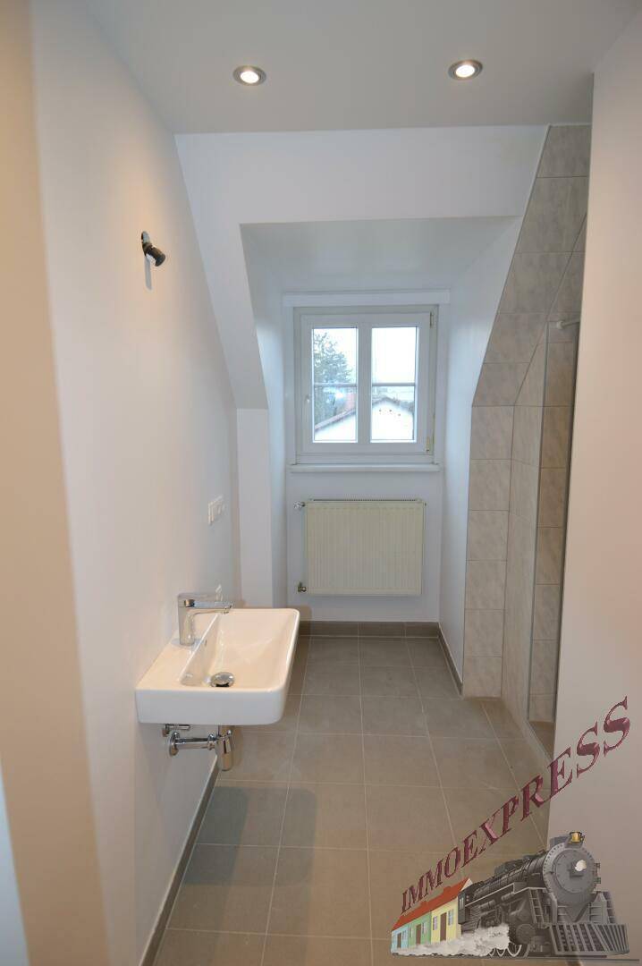 Modernes Badezimmer mit Waschbecken, Handtuchheizkörper und Fenster.