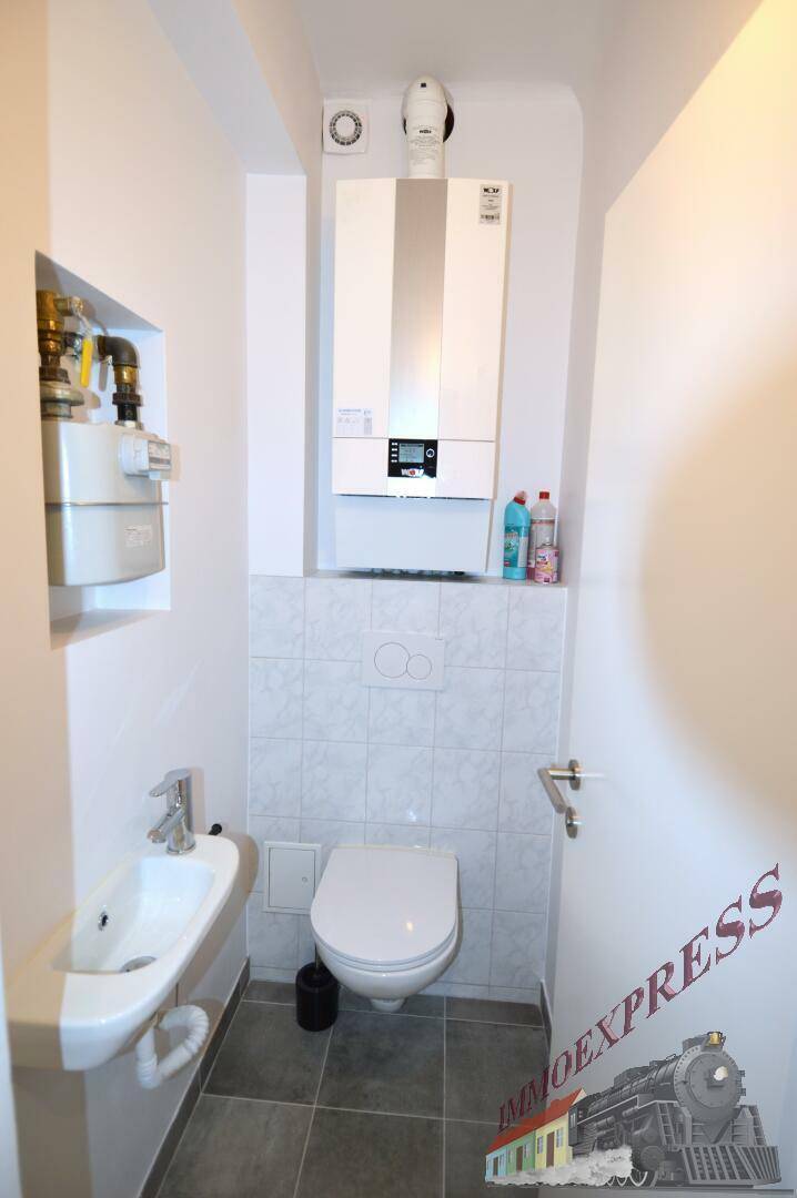 Kleines Gäste-WC mit Wand-WC, Waschbecken und Gastherme an der Wand.