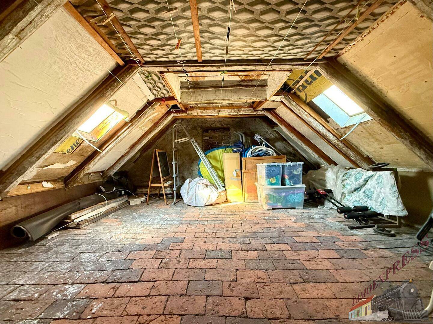 Unausgebauter Dachboden mit Ziegelboden und Dachfenstern, bietet viel Stauraum.