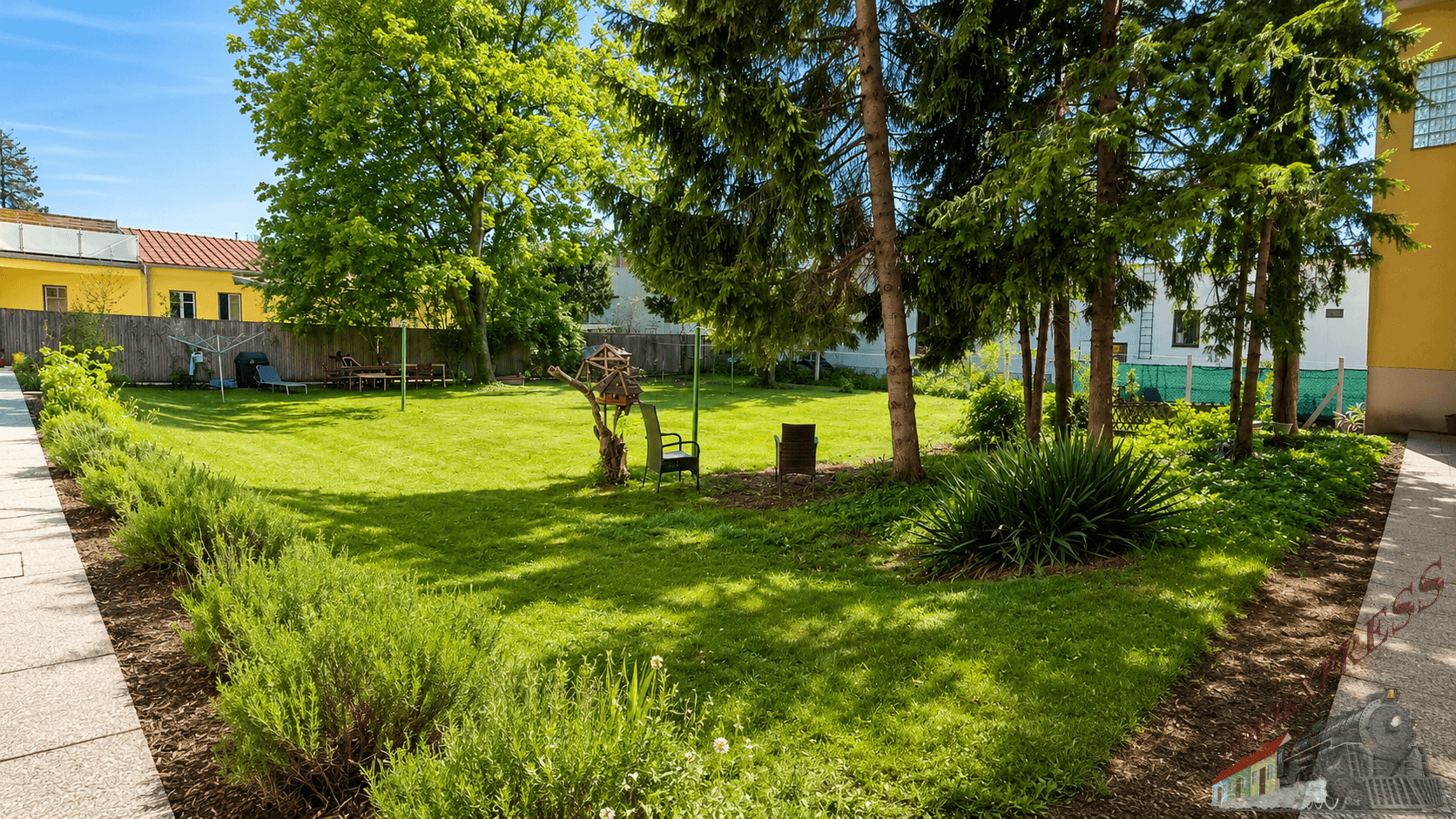 Gepflegter Gemeinschaftsgarten mit Rasenflächen, Bäumen und Sitzgelegenheiten im Freien.