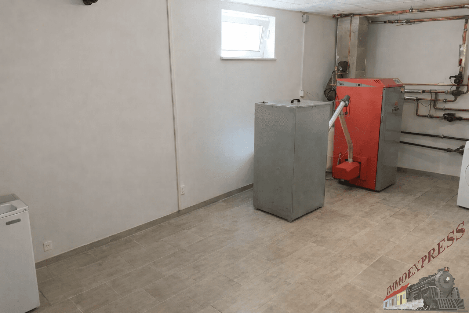Heizungsraum im Keller mit moderner Heizanlage und kleinem Fenster.