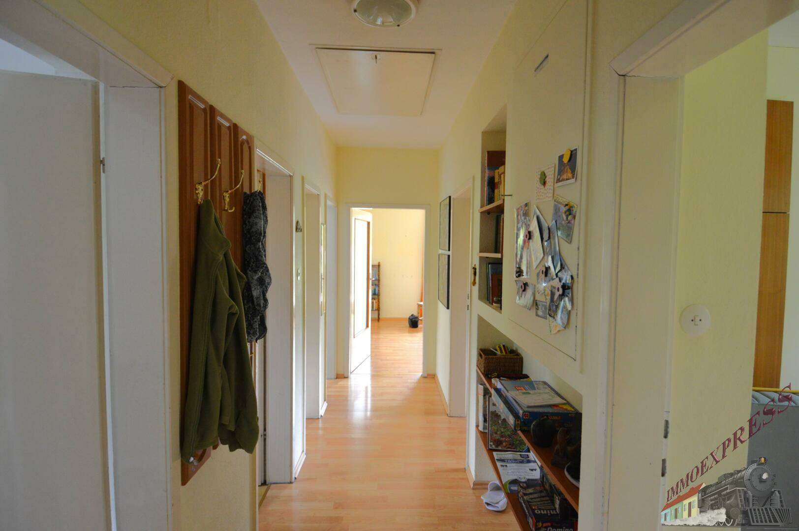 Heller Flur mit Holzboden, Garderobe und integrierten Regalen für zusätzlichen Stauraum.