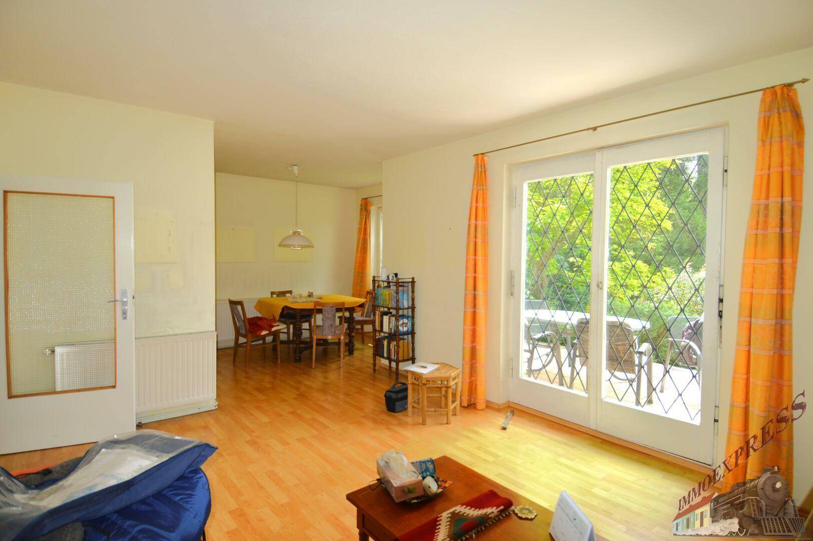 Heller Wohn- und Essbereich mit Holzboden und großen Glastüren zum Außenbereich.