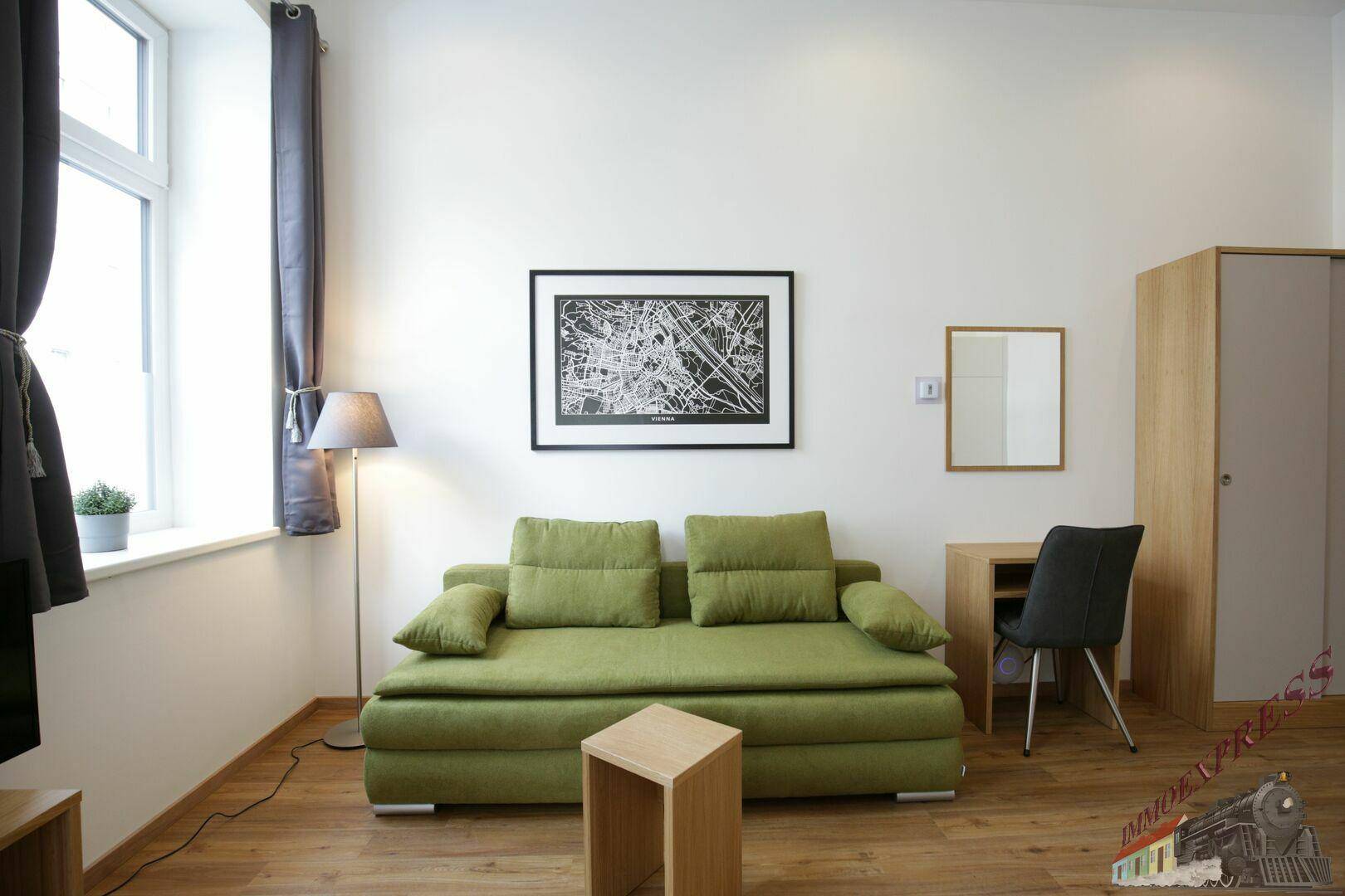 Gemütlicher Wohnbereich mit grünem Sofa, Schreibtisch und einem modernen Stadtplan an der Wand.