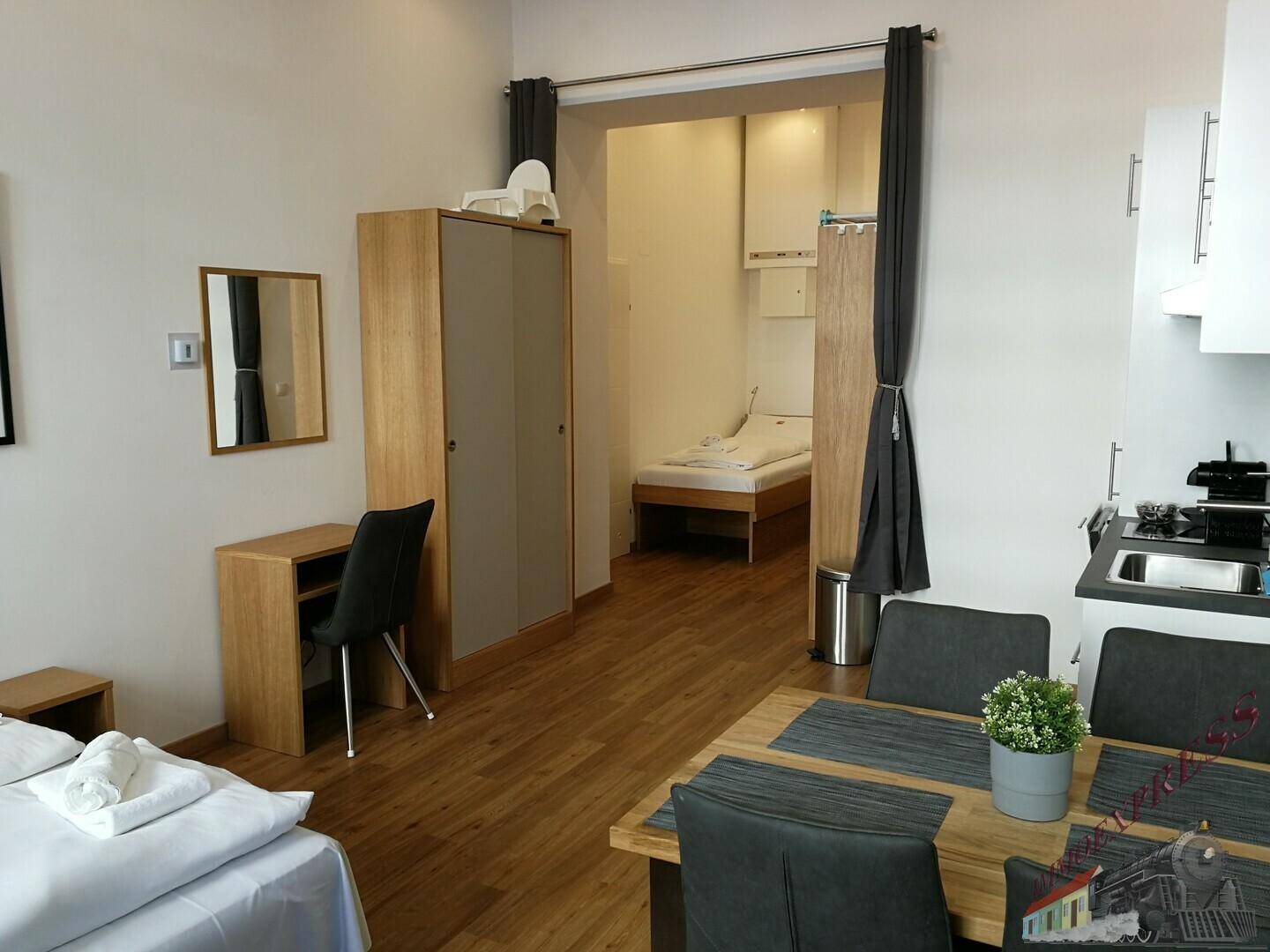 Offener Wohnbereich mit Esstisch, Schreibtisch und Blick auf den abgetrennten Schlafbereich.