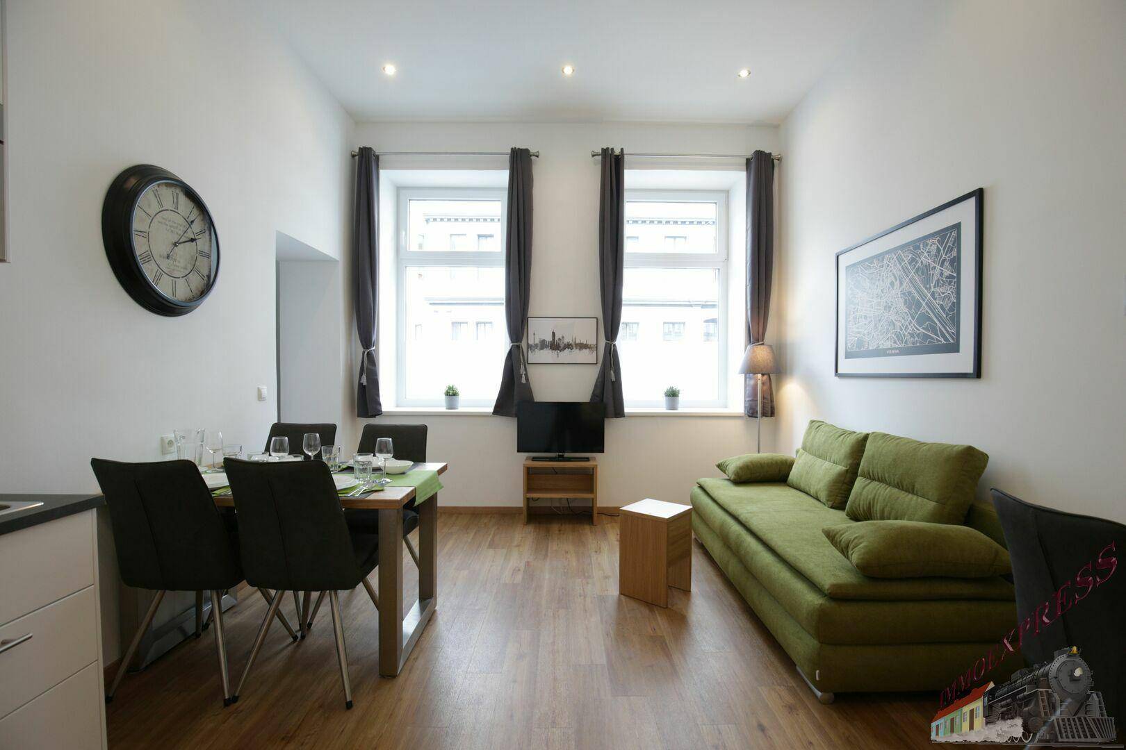 Geräumiger Wohn- und Essbereich mit Sofa, Esstisch und Holzboden, hell durch große Fenster.