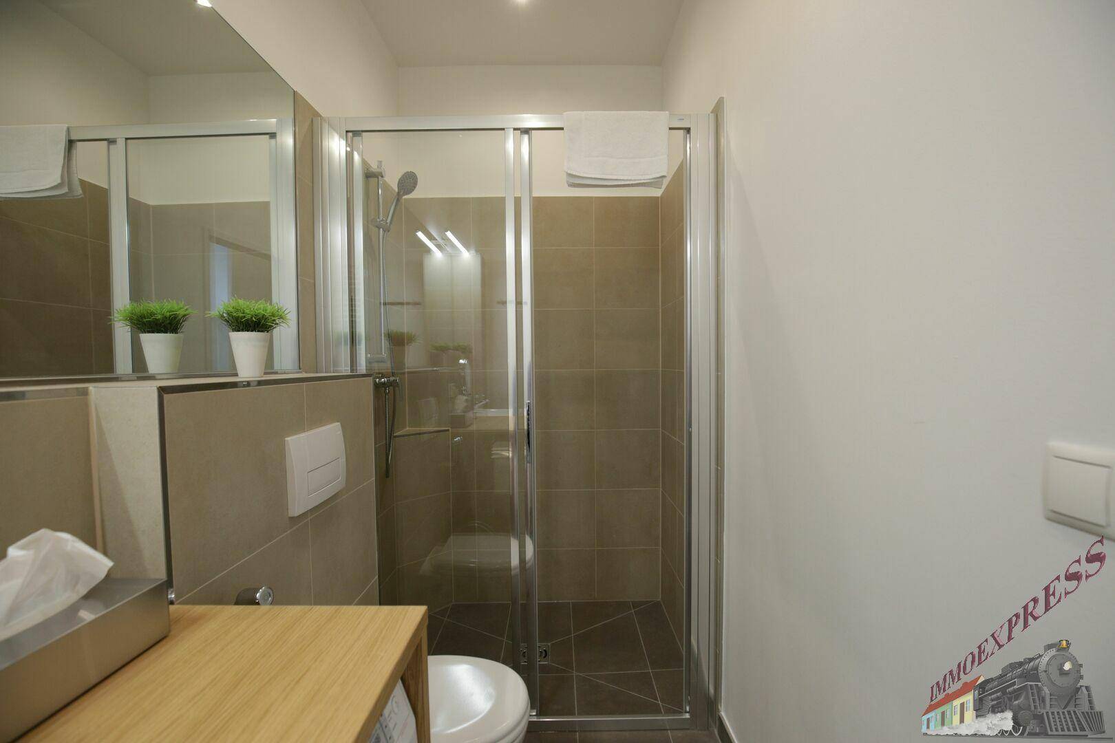 Modernes Badezimmer mit begehbarer Dusche, Wand-WC und hellen Fliesen.