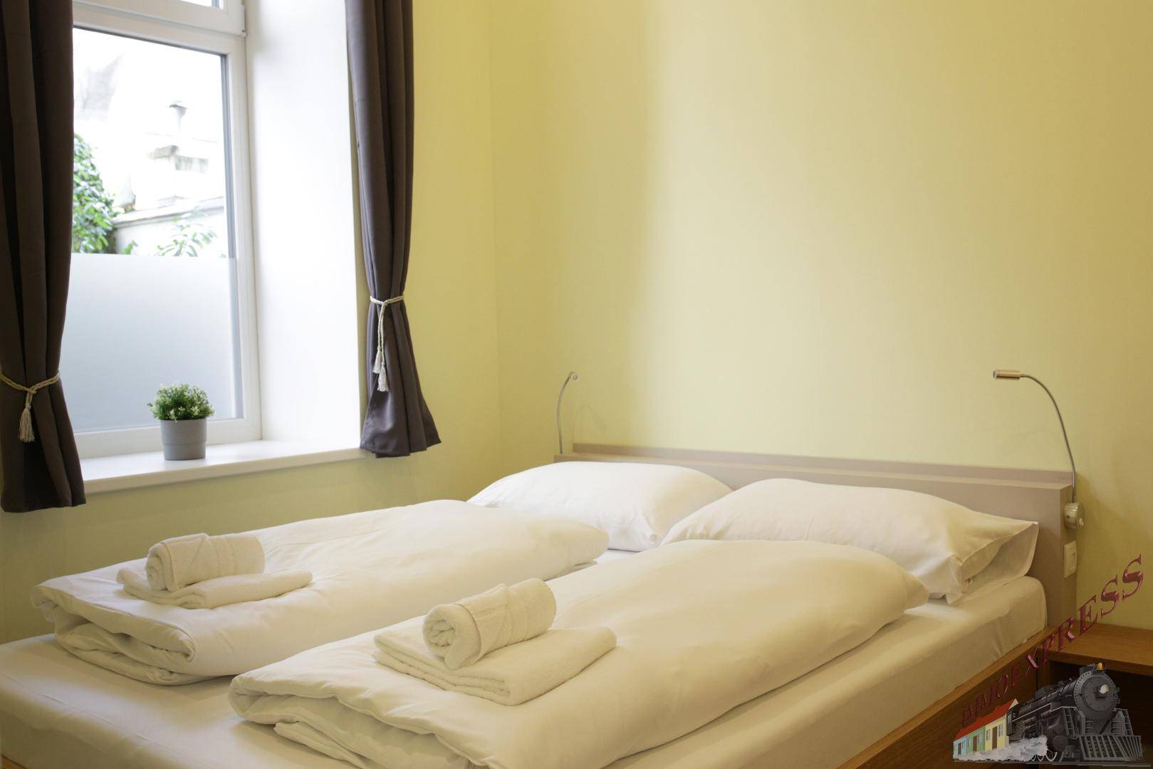 Helles Schlafzimmer mit zwei Einzelbetten, einem Fenster und Holzboden.