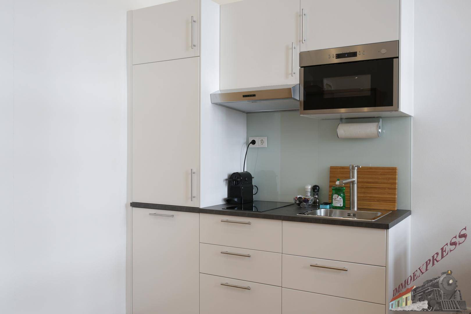 Moderne Küchenzeile mit integriertem Backofen und Mikrowelle, ideal für kleine Wohnungen.
