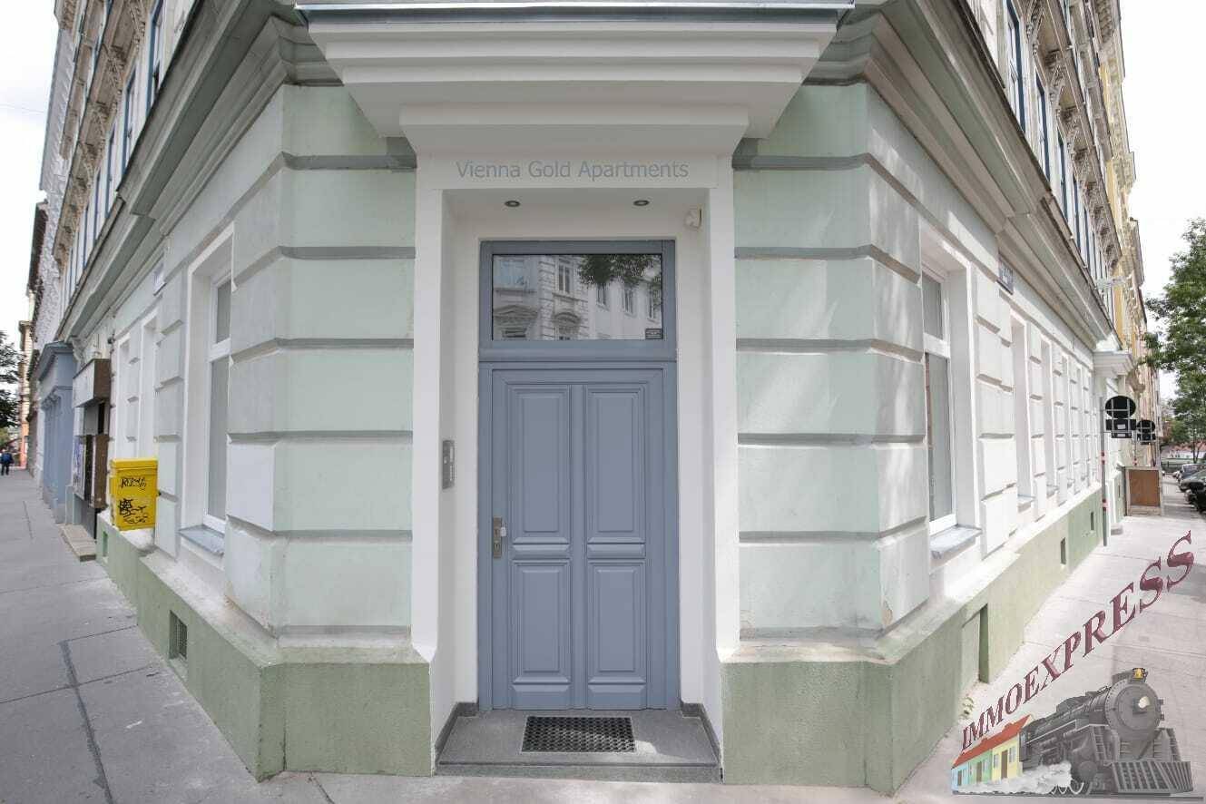 Eingangsbereich eines historischen Gebäudes mit einer eleganten blaugrauen Doppeltür und großen Fenstern.