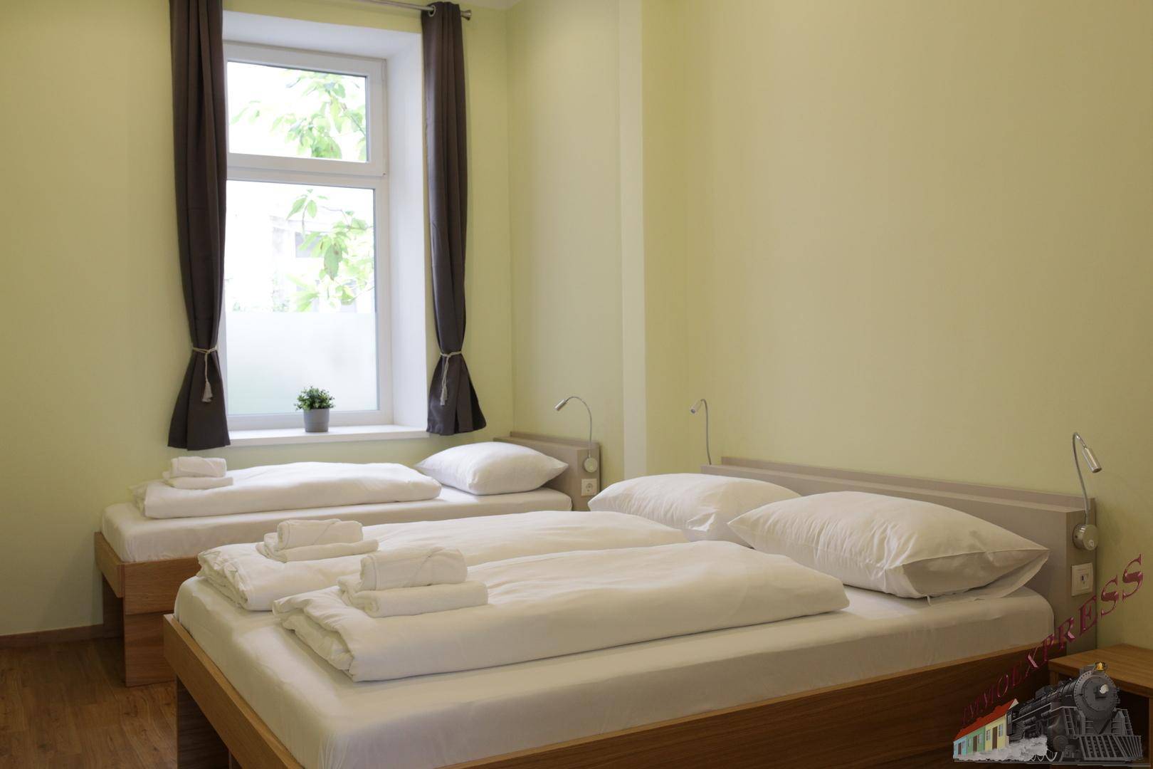 Helles Schlafzimmer mit zwei Einzelbetten, einem Fenster und Holzboden.