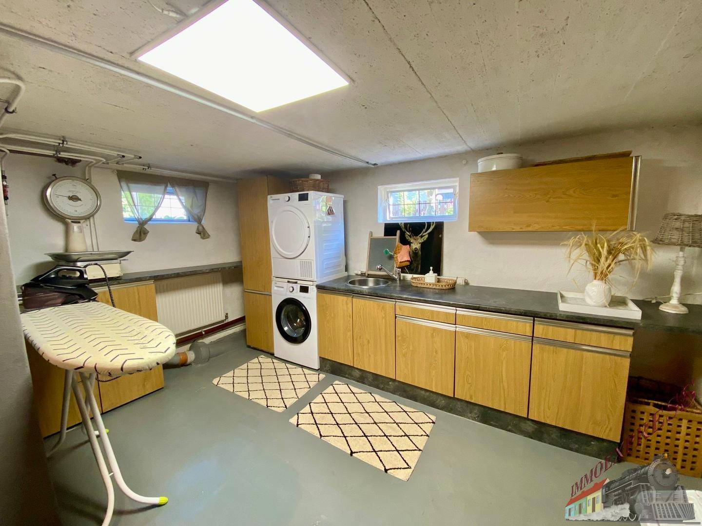 Praktischer Hauswirtschaftsraum im Keller mit Waschmaschine, Trockner und Bügelbrett.