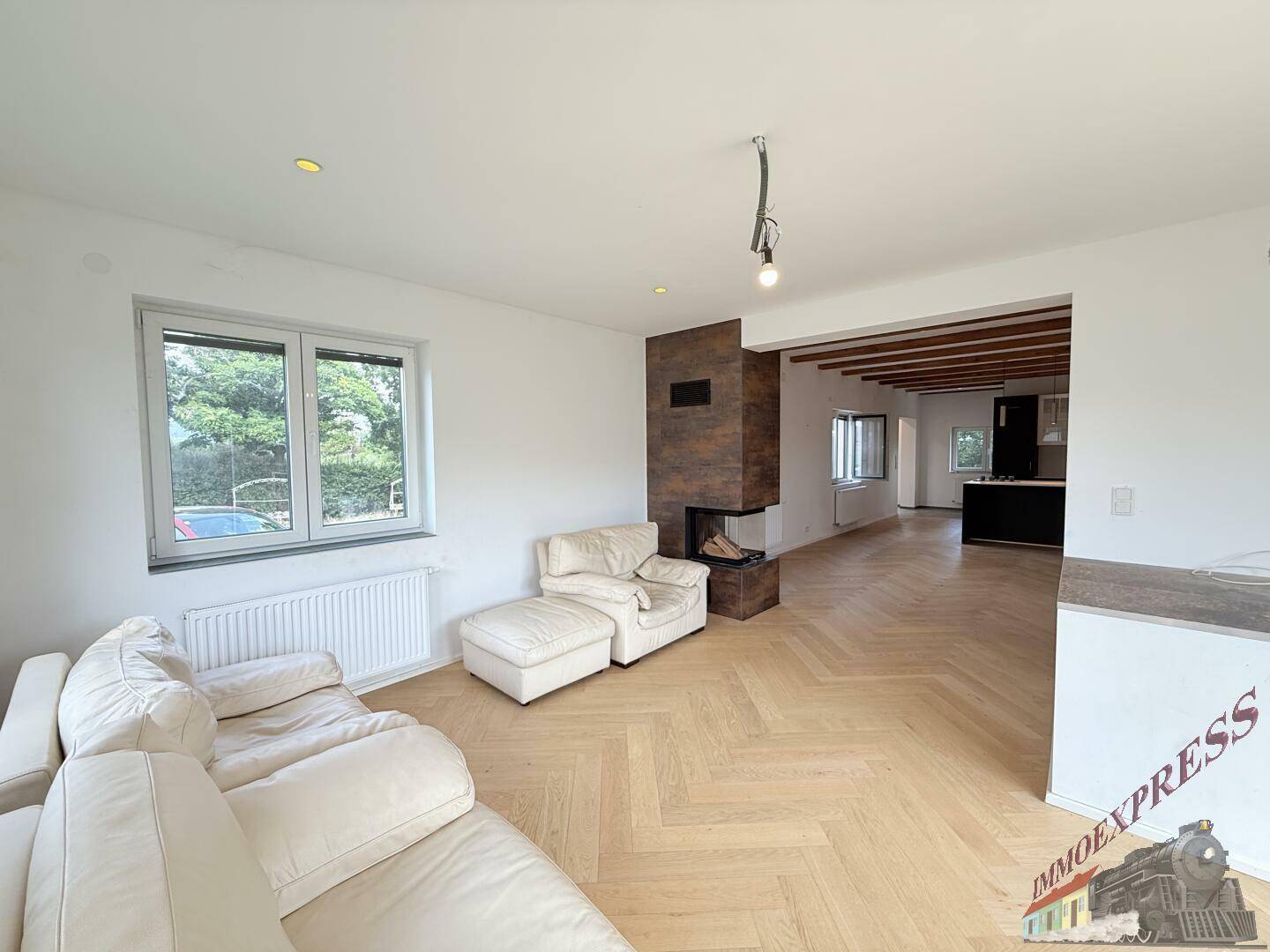 Heller Wohnbereich mit modernem Kamin, Fischgrätparkett und bequemen Sofas.