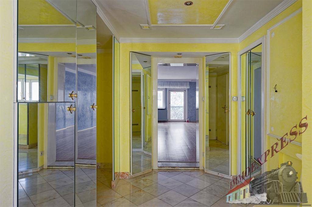 Heller Flur mit Spiegeltüren und gelben Wänden, der zu weiteren Räumen führt.