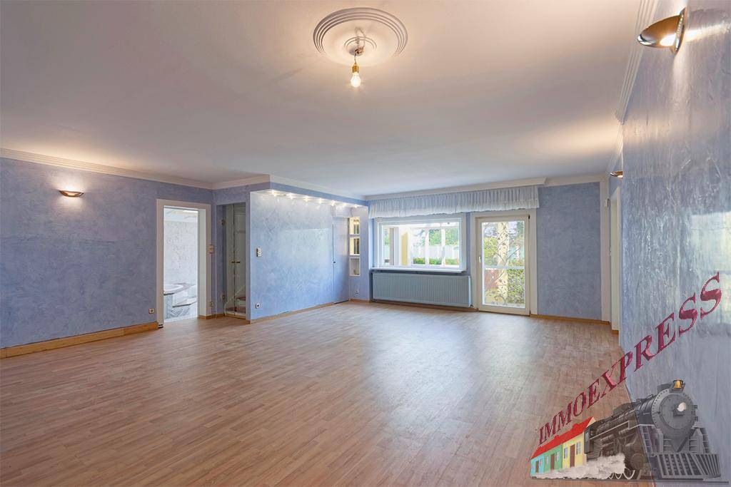 Geräumiges Wohnzimmer mit hellblau gestrichenen Wänden, Parkettboden und großen Fenstern.
