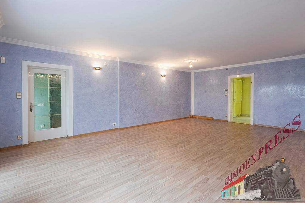 Weitläufiges Wohnzimmer mit Parkettboden und hellblauen Wänden, bereit zur individuellen Gestaltung.
