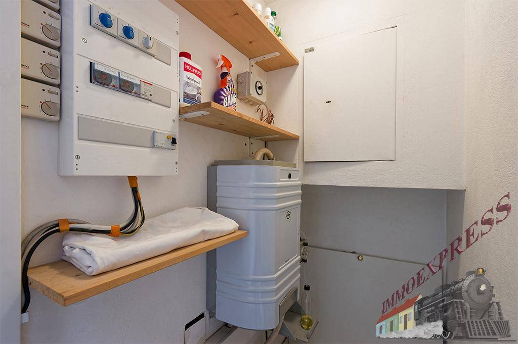 Kleiner Abstellraum mit Sicherungskasten, Regalen und Warmwasserboiler.