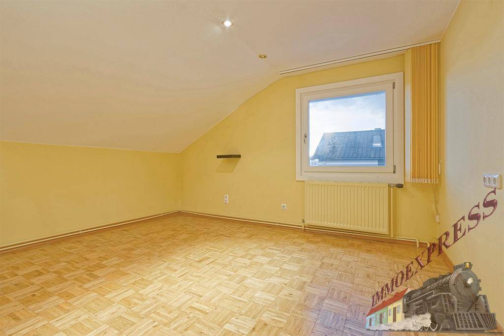 Dachzimmer mit gelben Wänden, Parkettboden und Fenster mit Blick nach draußen.