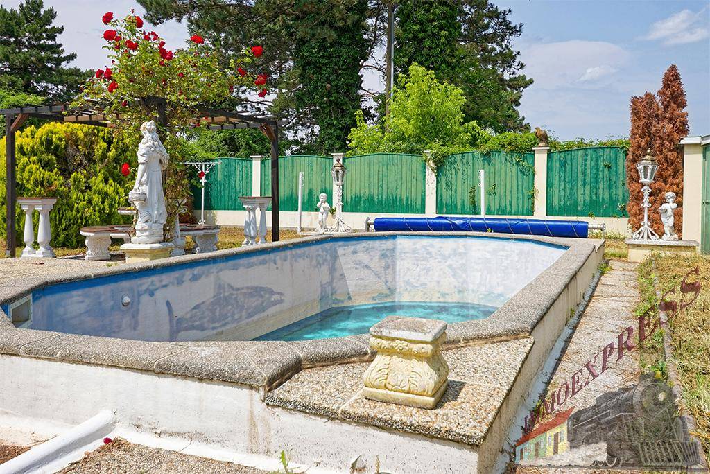 Außenpool im Gartenbereich mit dekorativen Statuen und umgebender Grünfläche, bereit zur Nutzung.