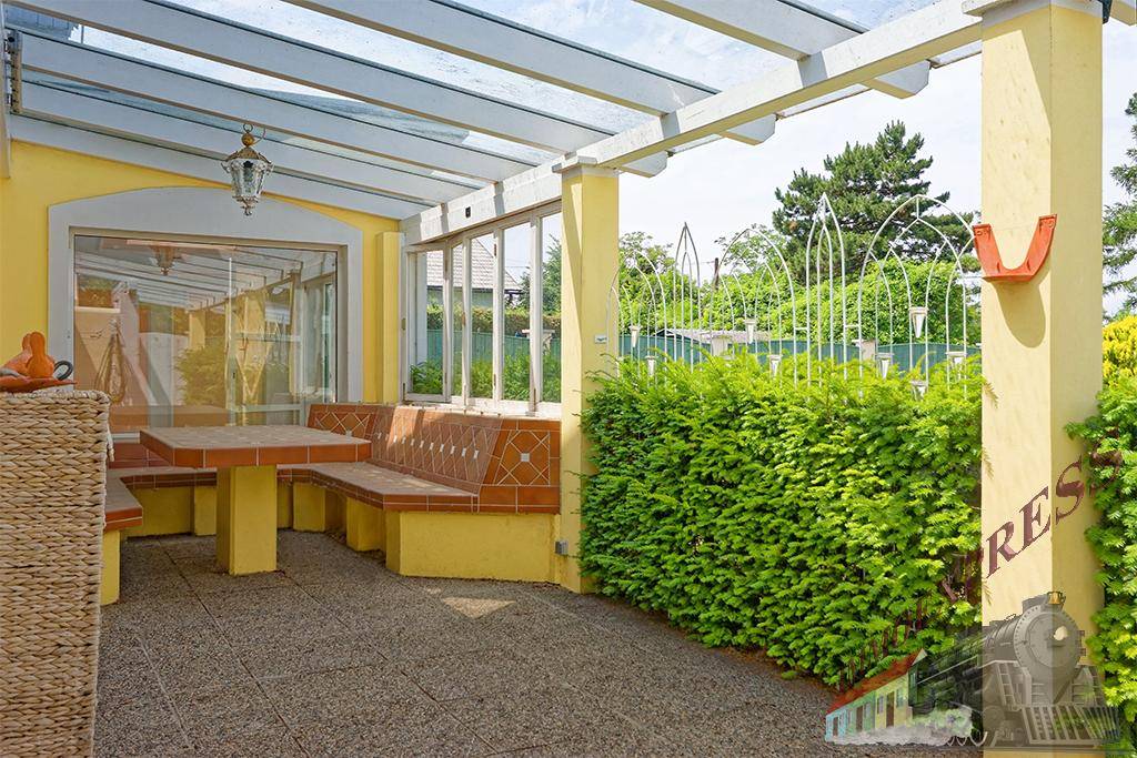 Überdachte Terrasse mit festen Sitzgelegenheiten und Blick in den grünen Garten, ideal für Entspannung.