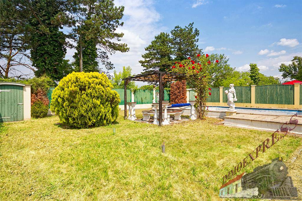 Großer Garten mit Rasenfläche, Bäumen, Pergola und einem Pool im Hintergrund, ideal für Familien.
