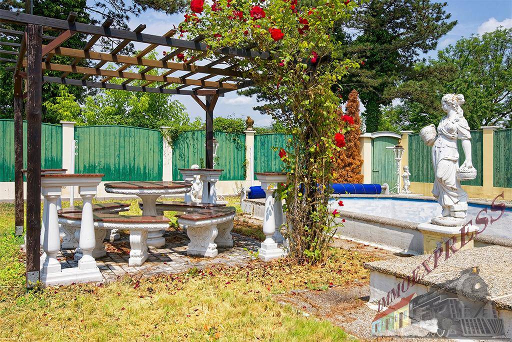 Gartenbereich mit Pergola, Steintischgruppe und Rosensträuchern neben dem Pool, sehr idyllisch.