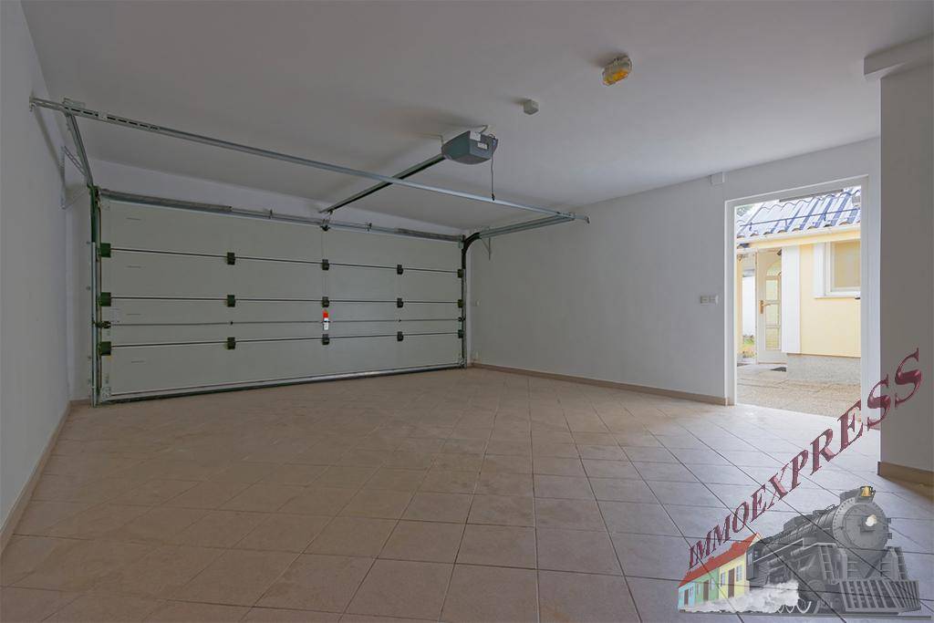 Geräumige Garage mit Fliesenboden und automatischem Garagentor, direkt am Haus gelegen.