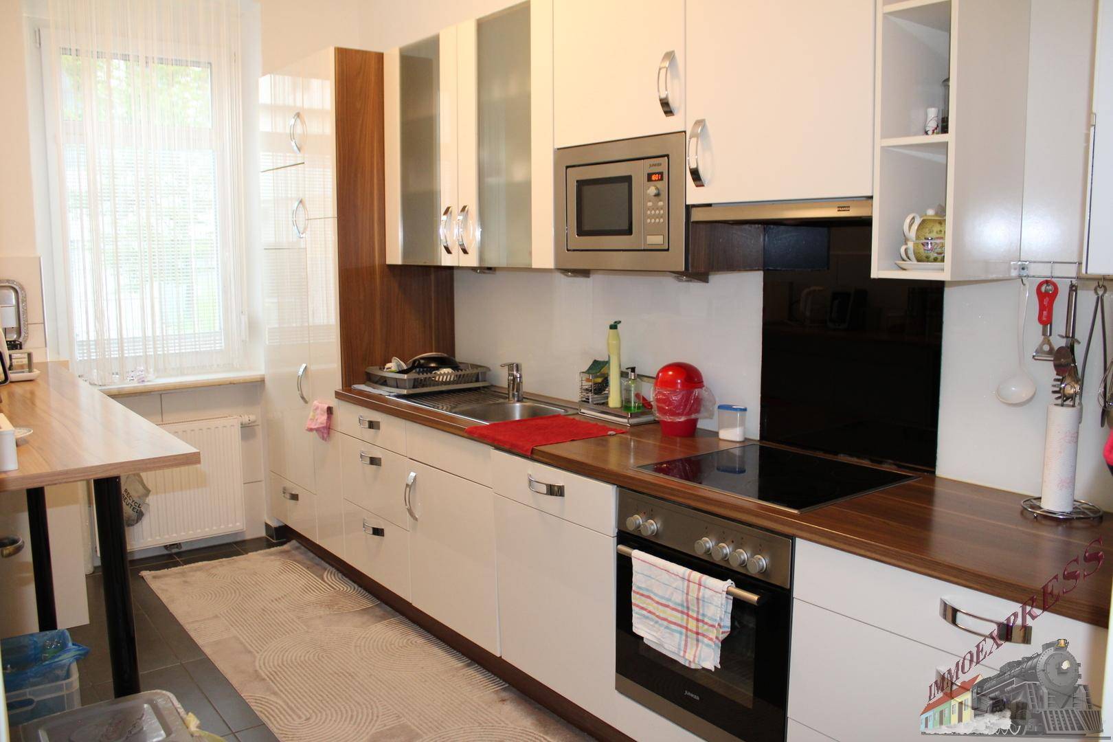 Moderne Küche mit weißen Hochglanzfronten, Holzarbeitsplatte und integrierten Geräten für komfortables Kochen.