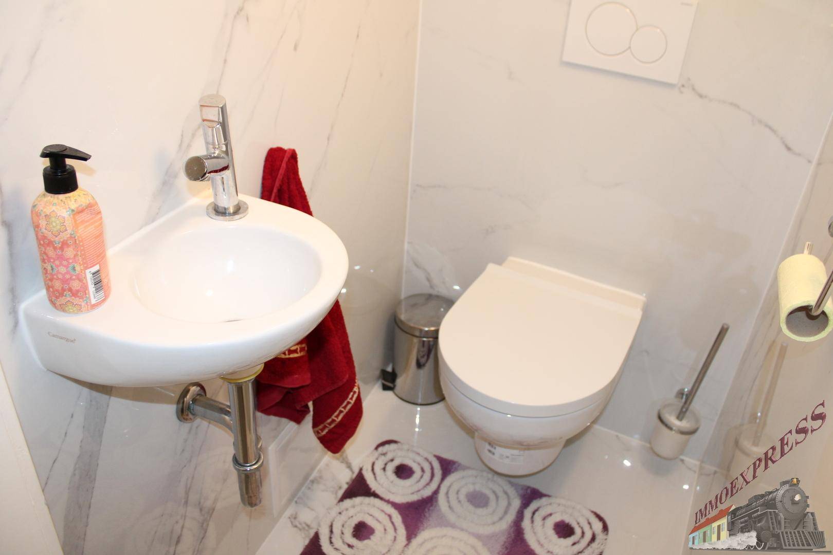 Kleines Gäste-WC mit Wand-WC und Eckwaschbecken, ausgestattet mit Marmorfliesen.