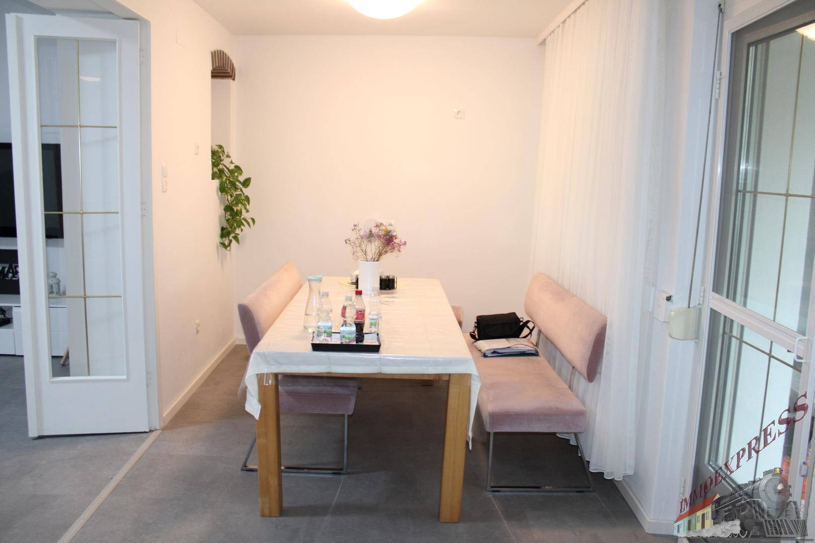 Heller Essbereich mit modernem Holztisch, gepolsterten Bänken und Zugang zum Außenbereich.