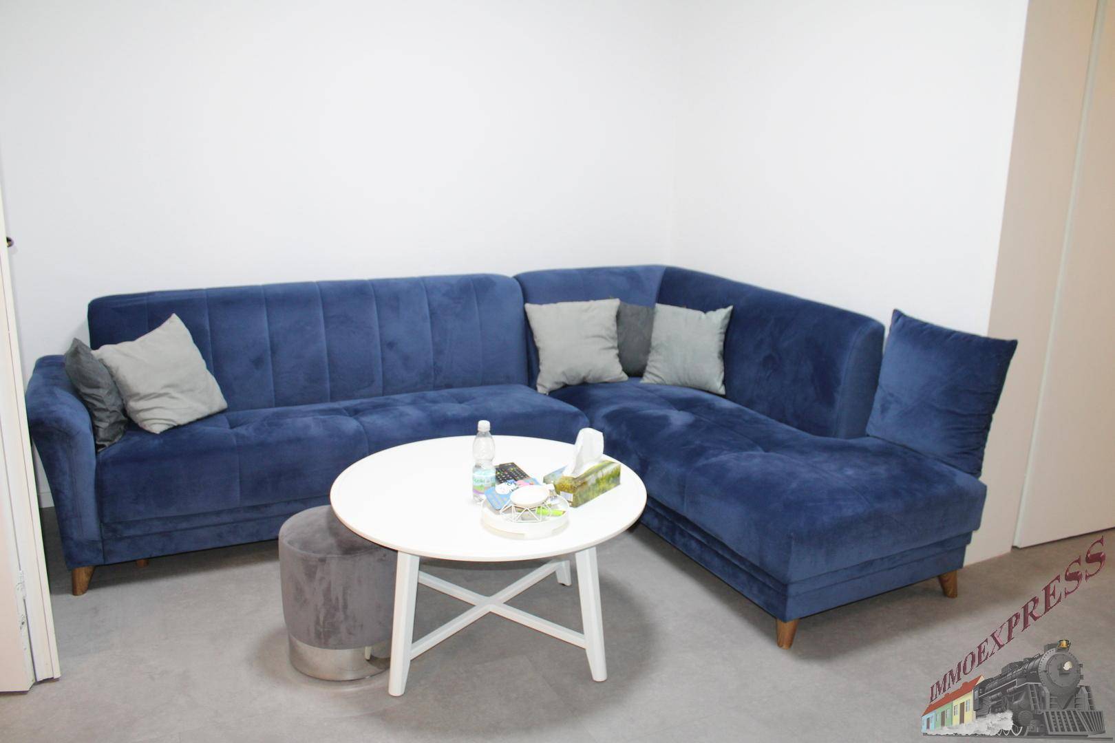 Gemütliches Wohnzimmer mit einem großen blauen Ecksofa und einem runden Couchtisch.