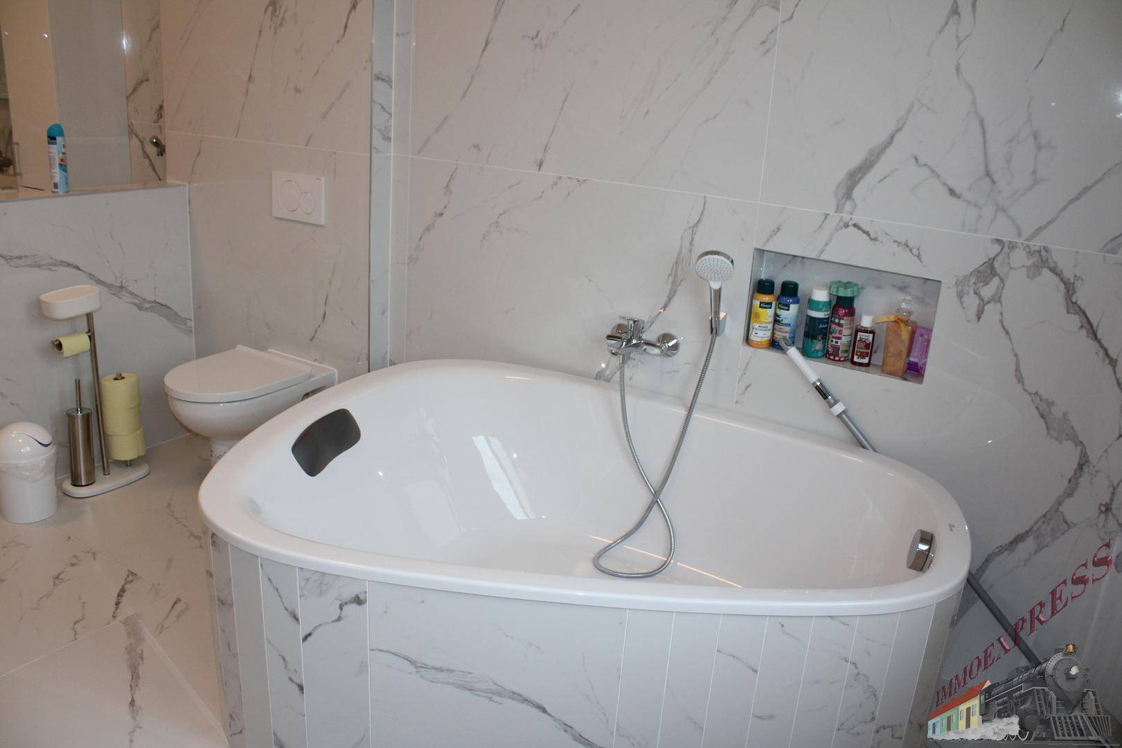 Elegantes Badezimmer mit ovaler Badewanne, Wand-WC und hochwertigen Marmorfliesen für ein luxuriöses Ambiente.
