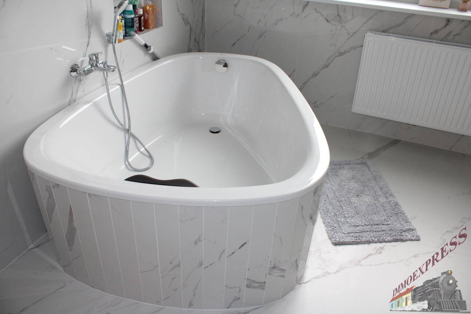 Modernes Badezimmer mit ovaler Badewanne und eleganten Marmorfliesen an Wänden und Boden.